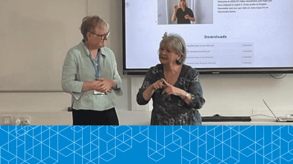 A picture of two middle age women, Emma (Past Chair) and Wendy on right side. Wendy was talking in sign language. There a powerpoint in the background.
